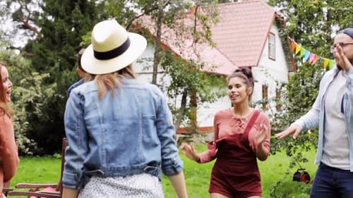 Happy friends dancing together at groovy summer garden party