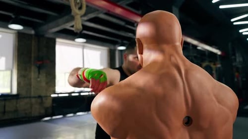 in a Boxing Fight Club Senior Muscular Trainer in a Black Tshirt and with Multicolored Bandages is