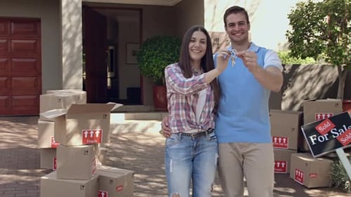 Happy Couple Holding Keys Outside Their New Home