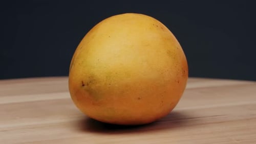 Two Mangoes a Food Staple are Placed on a Wooden Table These Natural Fruits are Produced From a
