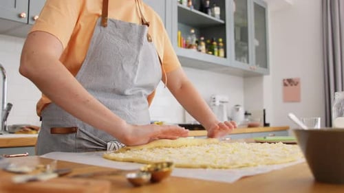 Woman Rolling Dough with Cheese in Kitchen