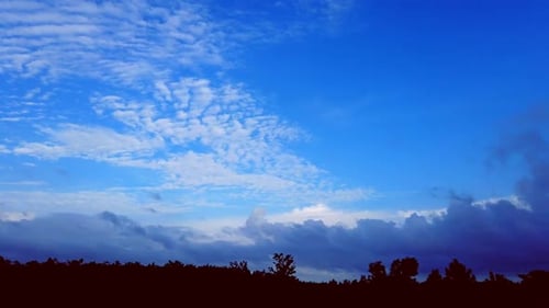 Mesmerising cloud movement in blue sky over forest line time-lapse