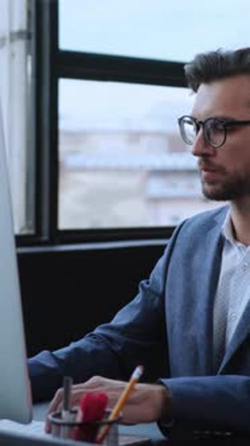 A Focused and Professional Individual Engaged in Working on a Computer in a Modern Office Setting