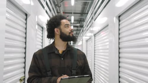Darkskinned Man Putting Information Into Tablet Examinating Self Storage Units