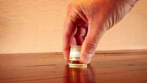 Close-up on hand counting stacked gold coins on wood tabletop