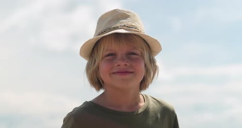 Blonde Boy Smiling in Straw Hat Outdoors