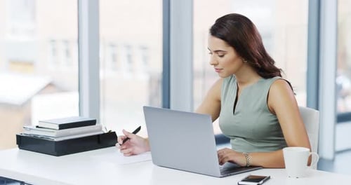 4k video footage of an attractive young businesswoman writing notes while working in her office