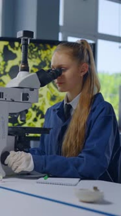 Teenage Girl Works with Microscope in Science Lab
