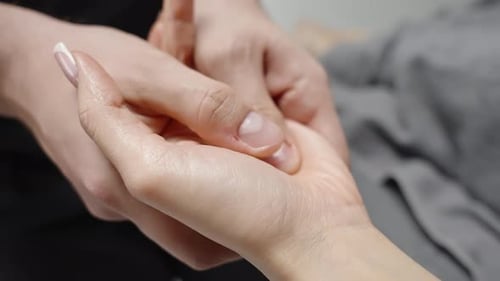 Nahaufnahme einer beruhigenden Handmassage, bei der ein Praktiker Daumendruck auf die Handfläche ausübt und