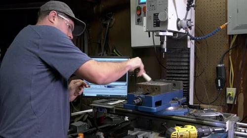 Operator wearing safety goggles while cleaning his vise below a drilling with a brush.