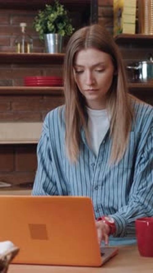 Woman Working on Laptop in Kitchen