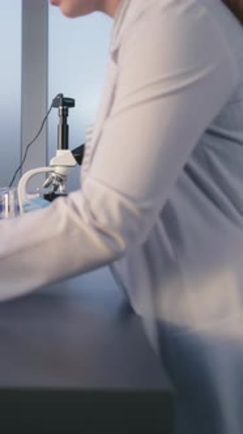 Adult Man Works Intently in a Lab with Microscope