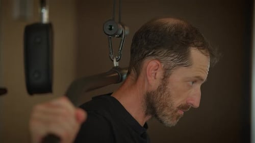 A Focused Man Actively Engaged in Exercising with Various Equipment in a Modern Gym Facility