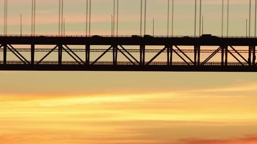 Schwarze Silhouette einer zweistöckigen Hängebrücke vor dem Hintergrund eines Sonnenuntergangs