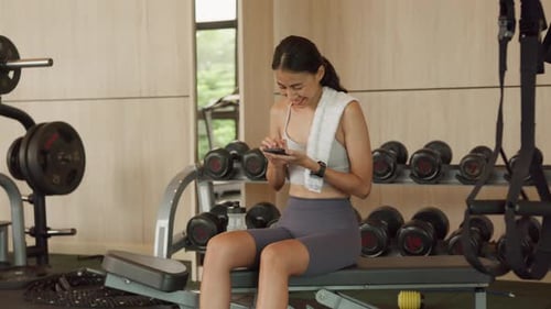 Woman Using Cell Phone During Gym Workout Break