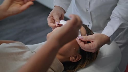 Cosmetologist Putting Protective Glasses at Woman Face in Beauty Clinic Closeup