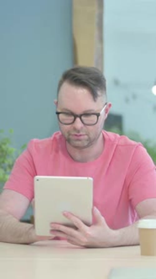 Man Using a Tablet Device at a Table