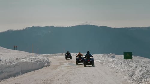 Road with quad bikes on driving down the path in winter.