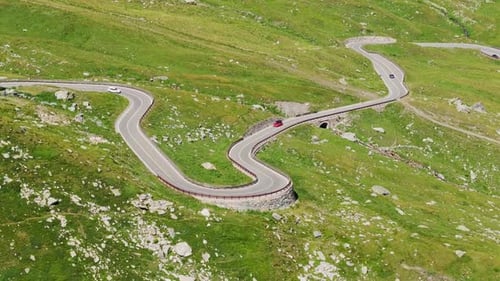 Winding Alpine Road Through Scenic Green Mountains on Sunny Day