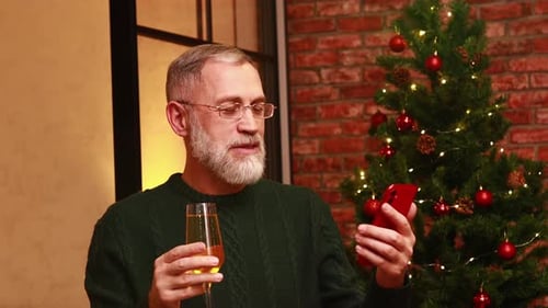 an Elderly Man in a Green Knitted Talking with Family By Phone Video Connection Near the Christmas