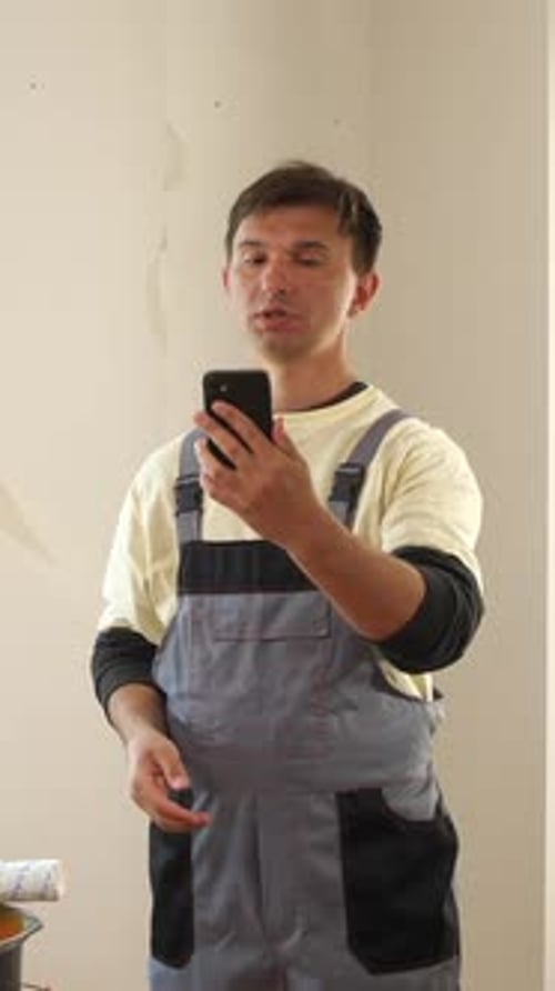Vertical Video Painter Gesturing and Showing Wall Damage During Video Call on Smartphone