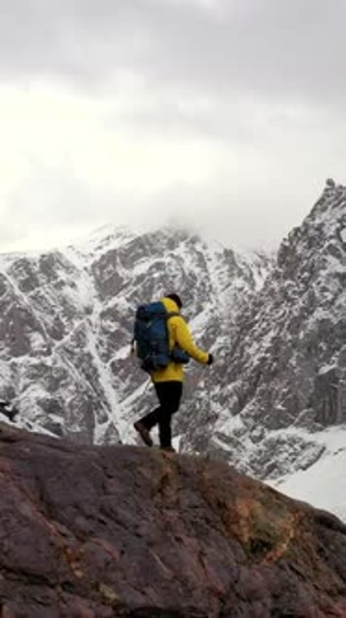 Hiker Walking on Colorful Rocks with Snowy Mountain in the Background