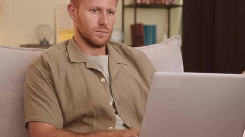 Man Working on Laptop While Sitting on Sofa