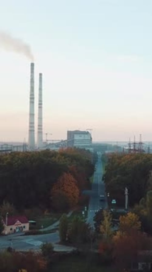 Blick auf das Kraftwerk mit zwei Rohren und der Straße dorthin mit der Pflanzung von Bäumen