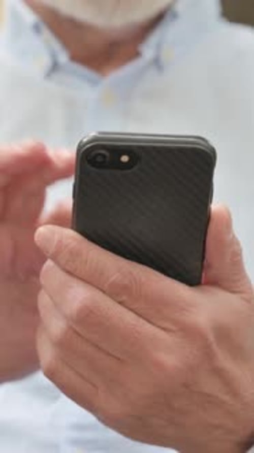 Close Up of Senior Old Man Browsing Smartphone while Sitting Outdoor on a Bench, vertical video