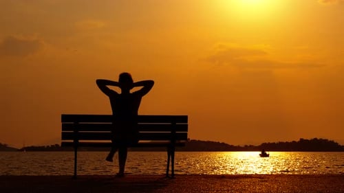 Silhouette Woman Relaxing on Bench at Sunset