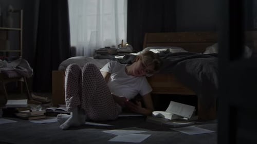 Woman Surrounded By Papers Scrolls Newsfeed on Smartphone