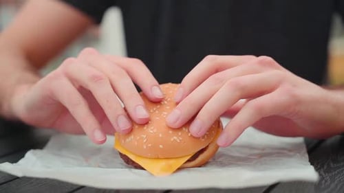 Slow motion young caucasian man bites into burger at home, cheeseburger eating enjoyment, close up p