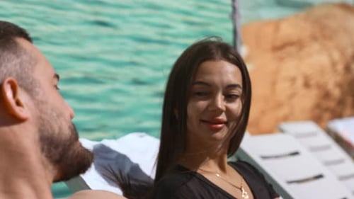 Couple Relaxing by Blue Pool on Sunny Day