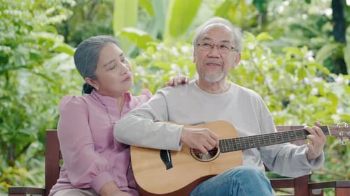 Elderly Couple Playing Guitar in Tropical Setting