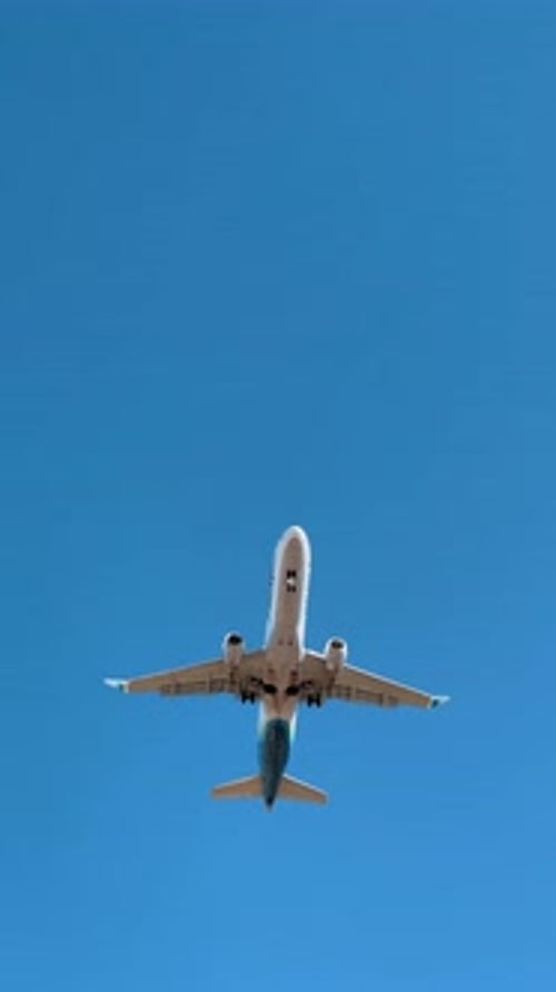 Bottom view of jet airplane landing against blue sky. Directly underneath view of a passenger