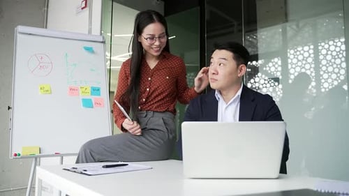 Young asian female employee flirts with a coworker at workplace in business office