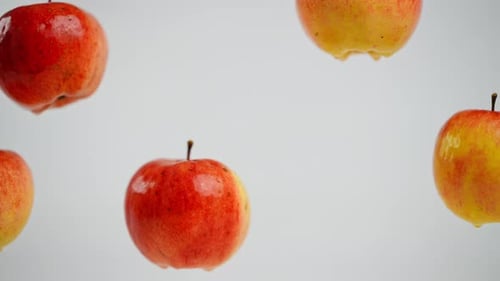 Fünf leckere Äpfel hängen auf weißem Hintergrund mit einer herunterfallenden Frucht, Nahaufnahme, köstliches Vitamin