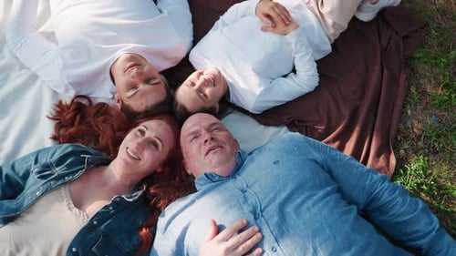 Aerial View Of Nature Loving Family Lying Down With Heads Joined Smiling Together