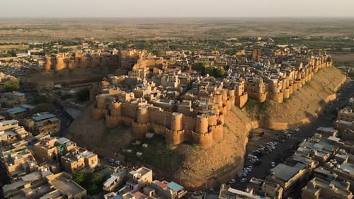 Aerial drone shot highlighting the intricate architecture of Jaisalmer Fort during a desert sunset.