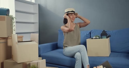 Asian woman in casual sitting on coach enjoy unpacking box stuff real estate purchase.