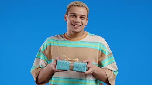 Smiling Man Holds Out Blue Wrapped Gift