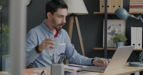 Motivierter IT-Spezialist, der mit Laptop tippt, Spaß an der Softwareentwicklung hat, arbeitet und Kaffee trinkt