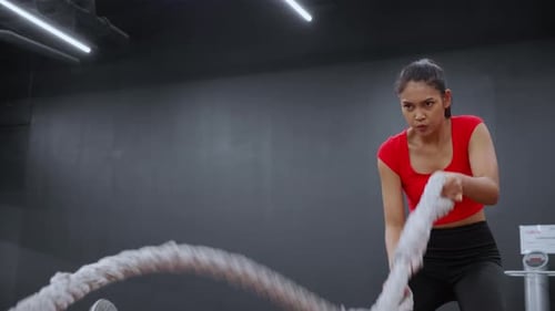 Young asian woman in sportswear doing exercise with rope in the fitness gym sport club.