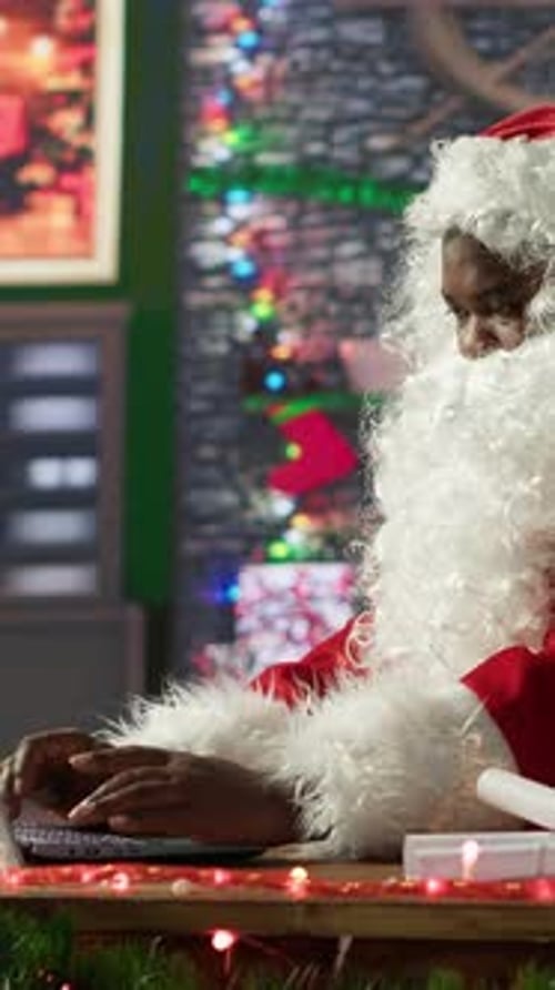 Vertical Video Santa Claus Uses a Laptop in His Festive Log Cabin Navigating Online Webpages