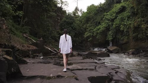 a Girl Walks By the River Through the Jungle