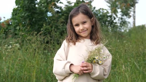 Smiling Girl Holding Wildflowers in a Meadow
