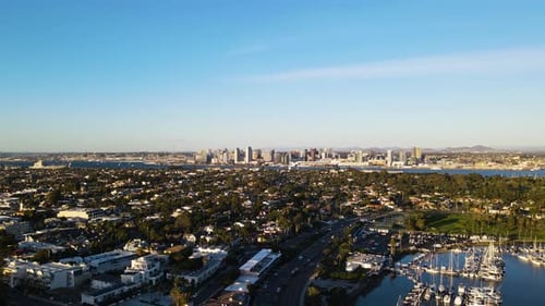 An aerial shot captures the San Diego skyline in the background, with a picturesque marina in the fo
