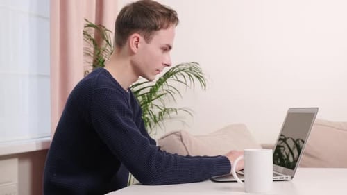 Young Adult Types on Laptop at Home