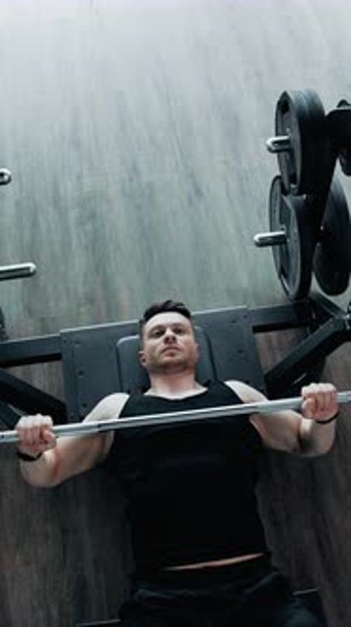 Man using barbell in the gym. Professional athlete doing workout with barbell in the hardcore gym