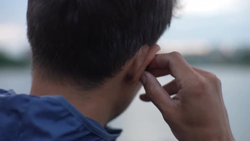 Close Up Cropped Shot of Unrecognizable Athletic Male Putting in Ear Wireless Earphones Getting